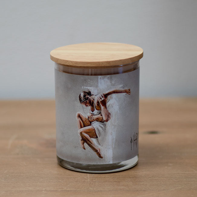 A vanilla scented wax candle with a cotton wick, housed in a clear glass jar with a wooden lid. The jar features an illustration of a king and a queen.