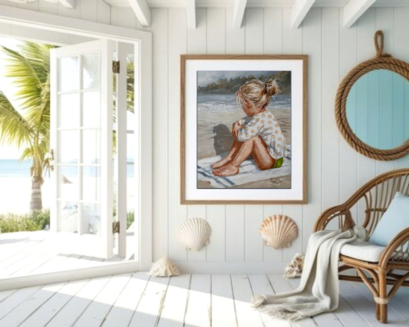 Framed artwork of a child on a beach in a room with white walls, a wicker chair, and shell decorations.
